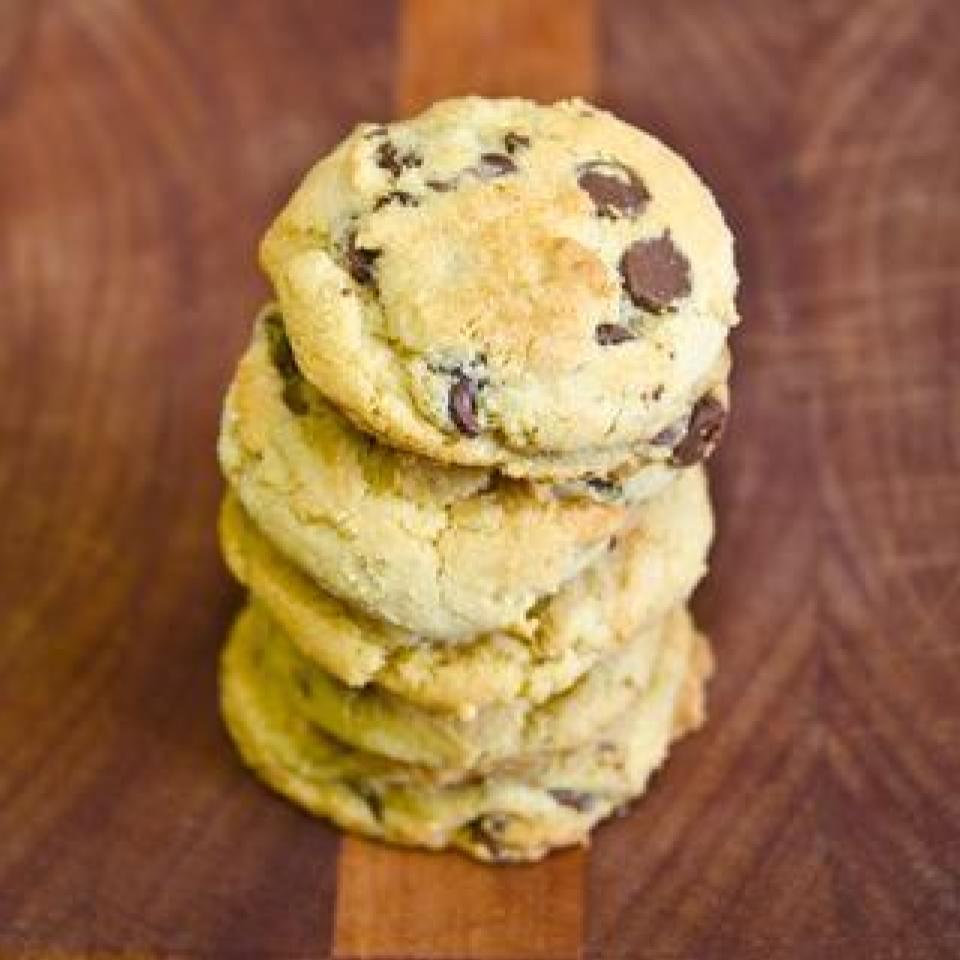 A stack of chocolate chip cookies is centered on a wooden cutting board
